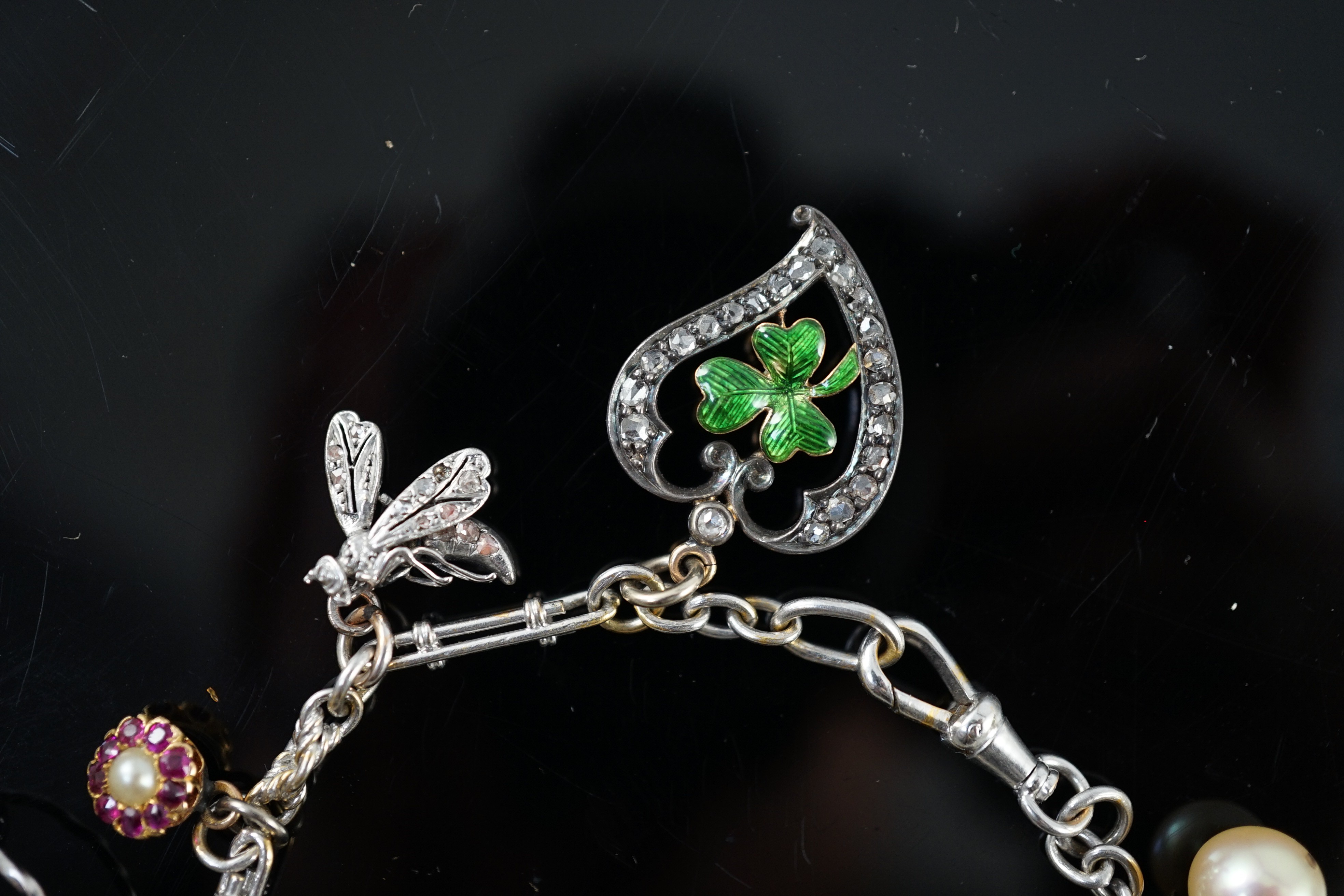 A French 18ct white gold circular and baton link charm bracelet, hung with eleven assorted charms